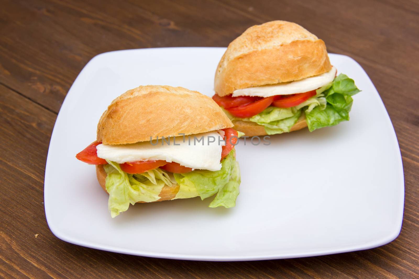 Sandwiches with tomato and cheese on plate over wooden table