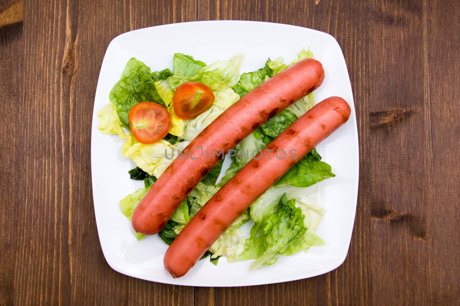 Sausages with salad on wood from above by spafra