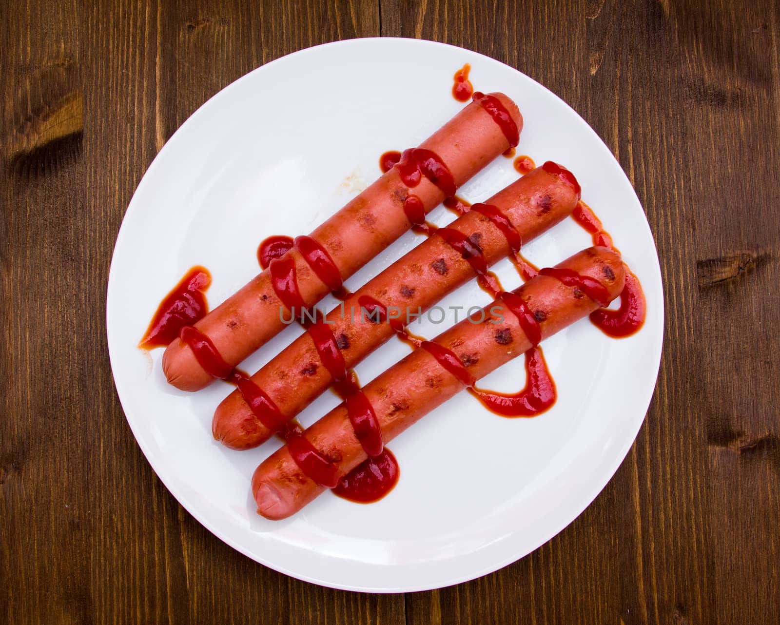 Sausages with tomato sauce on wooden table seen from above