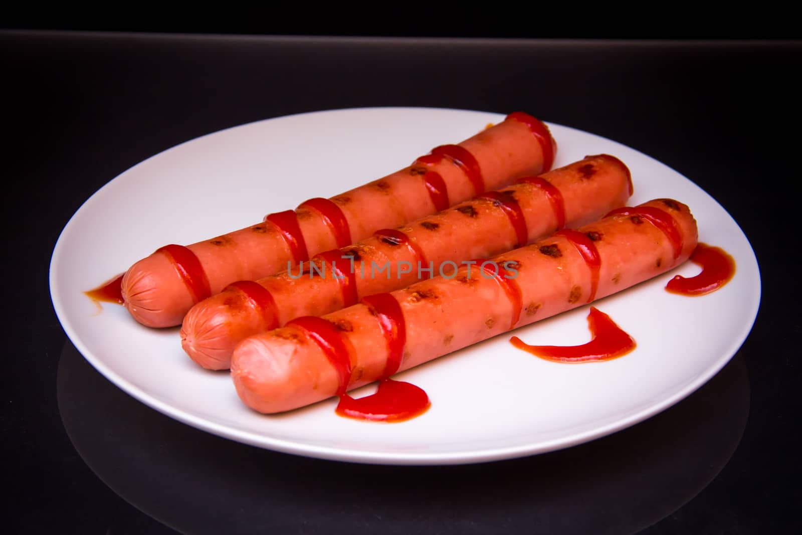 Sausages with tomato sauce on black by spafra