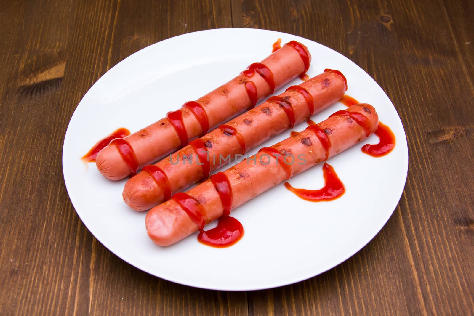 Sausages with tomato sauce on wooden table