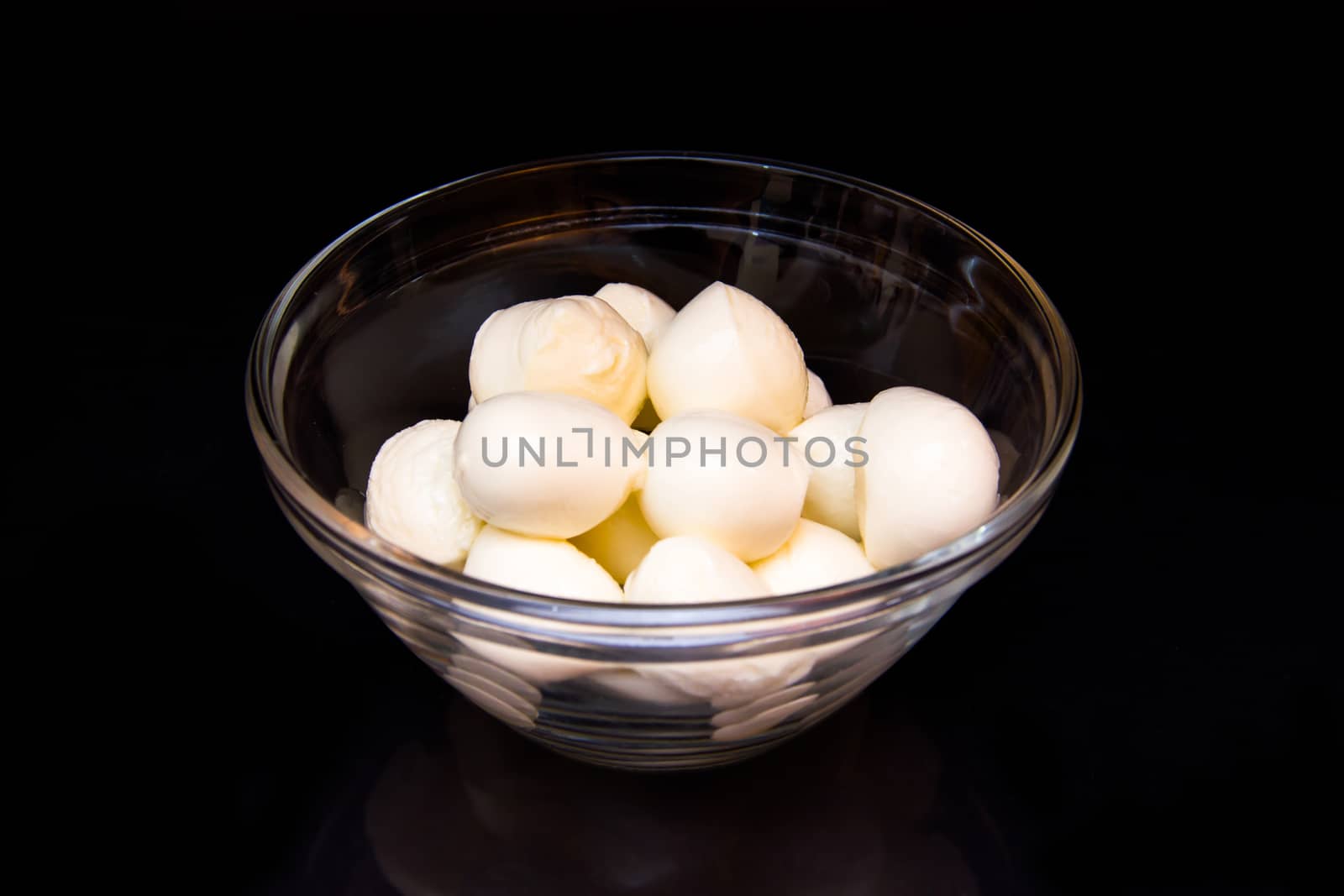 Small mozzarella in bowl on black background