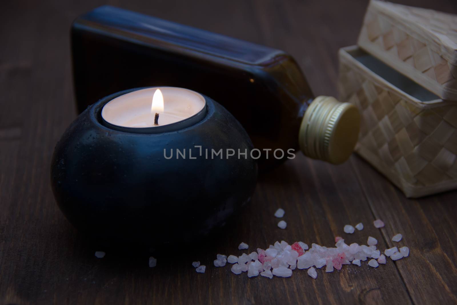 Candle with bath salts and oil on wooden table