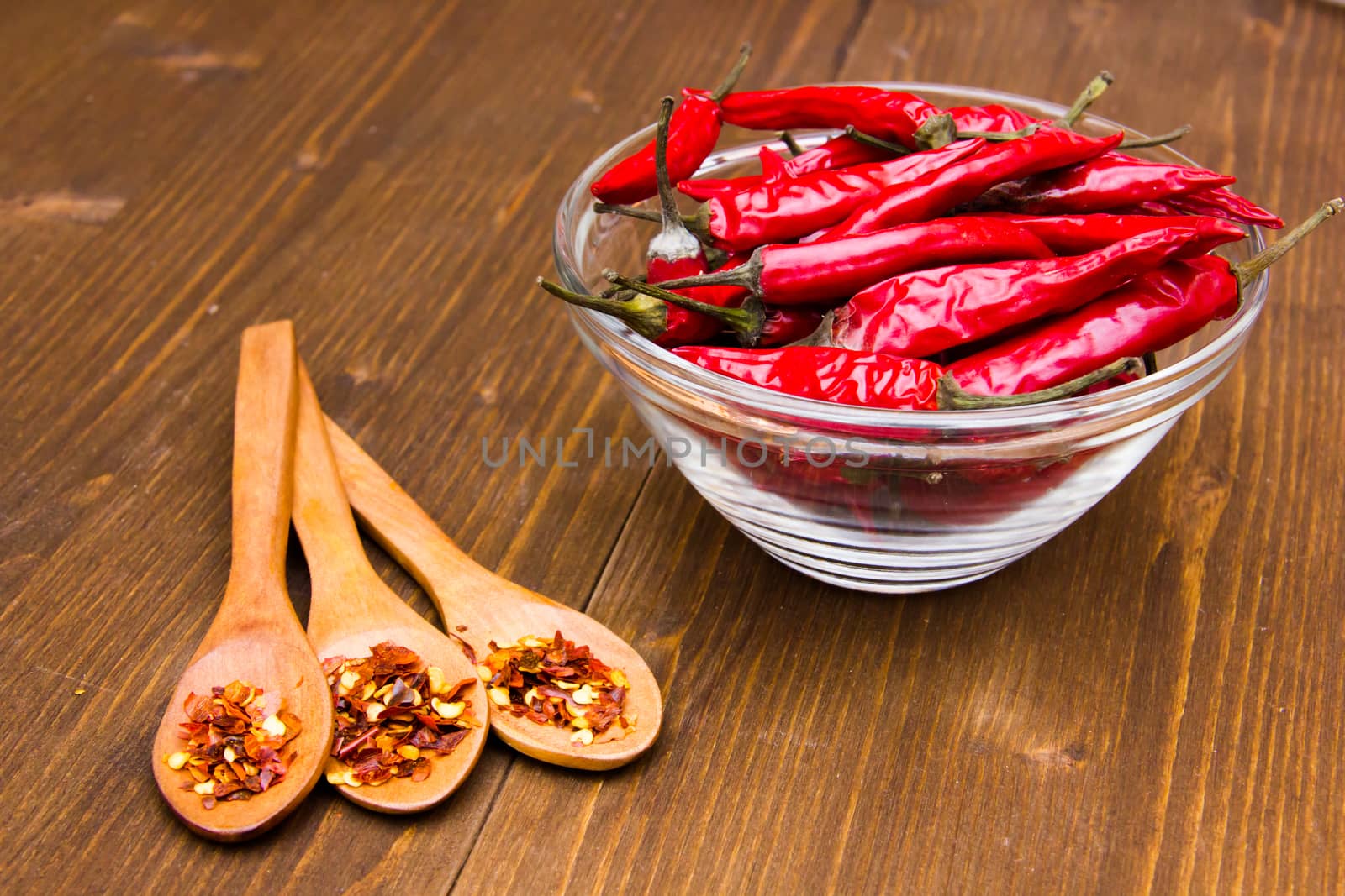Peppers on the bowl and spoons on wooden table