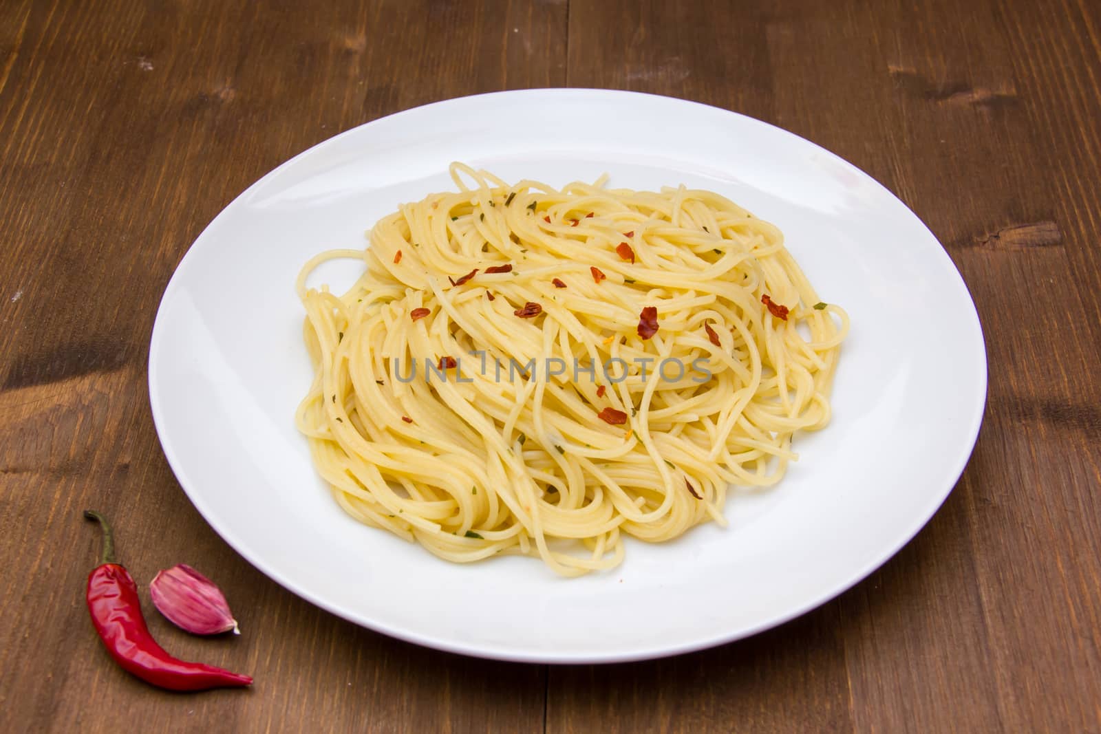 Spaghetti with garlic and chili peppers on wood by spafra