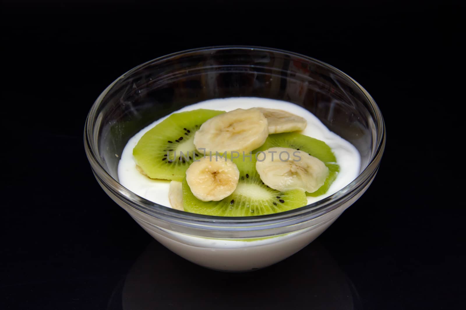 Yogurt with kiwi and banana on black background