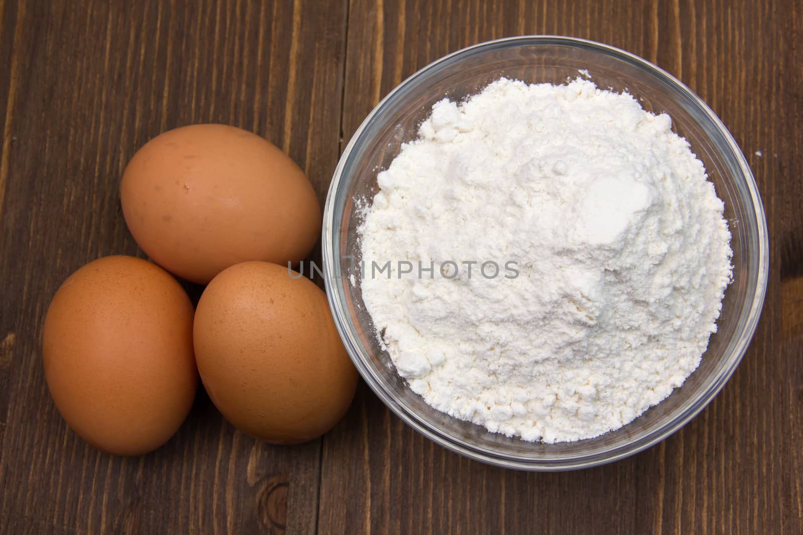 Eggs and flour on wood from above by spafra