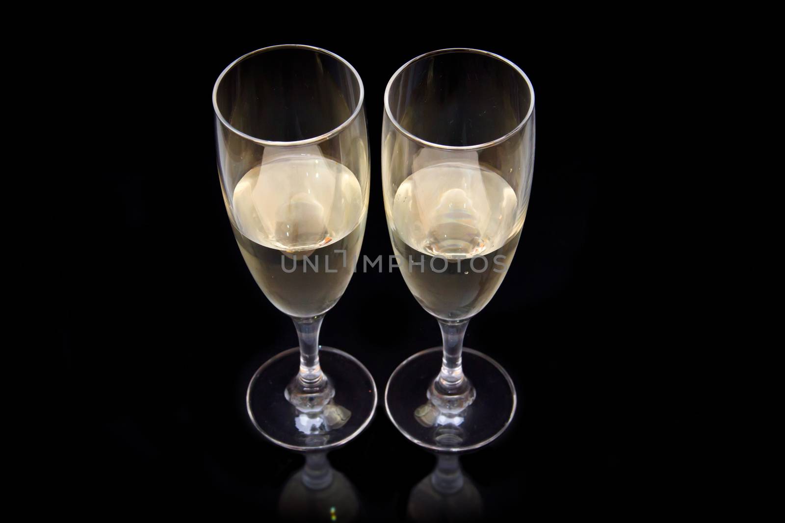 Flute with sparkling wine that is reflected on a black background