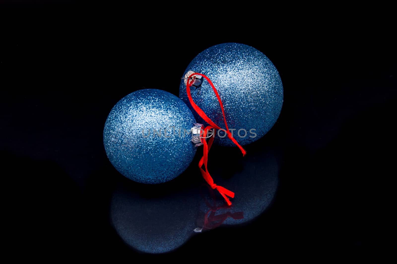 Christmas glitter balls that are reflected on a black background