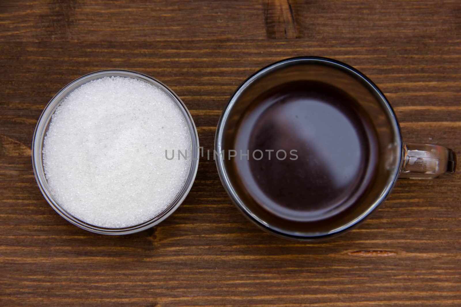 Cup of coffee and sugar on wooden seen from above
