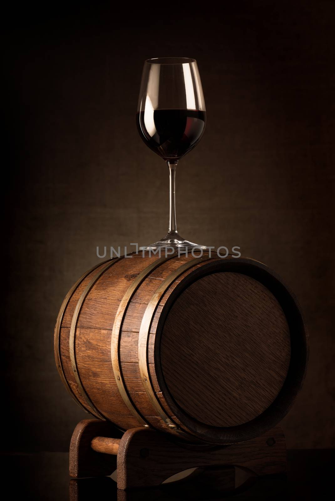 Wineglass with red wine on a wooden barrel