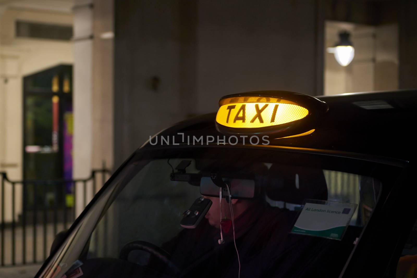 Low key detail of London black cab sign turned on at night.