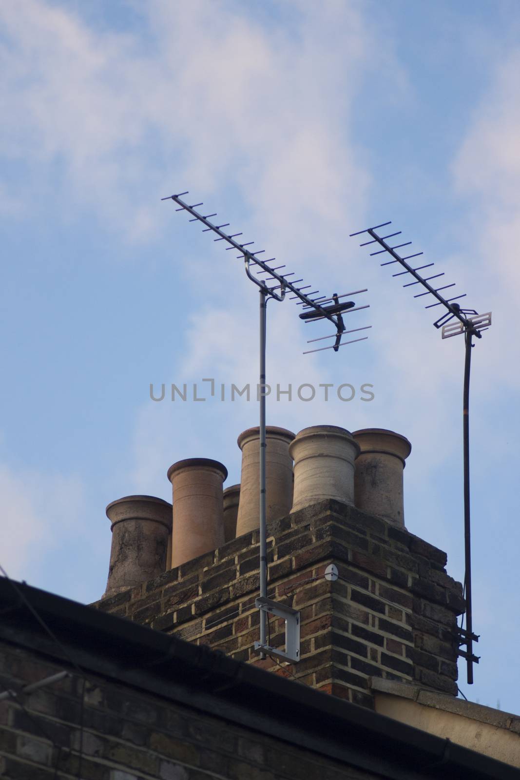 TV arial television antenna and chimney on roof of an urban high rise building and attractive blue purple dusk sunset sky in London England. 