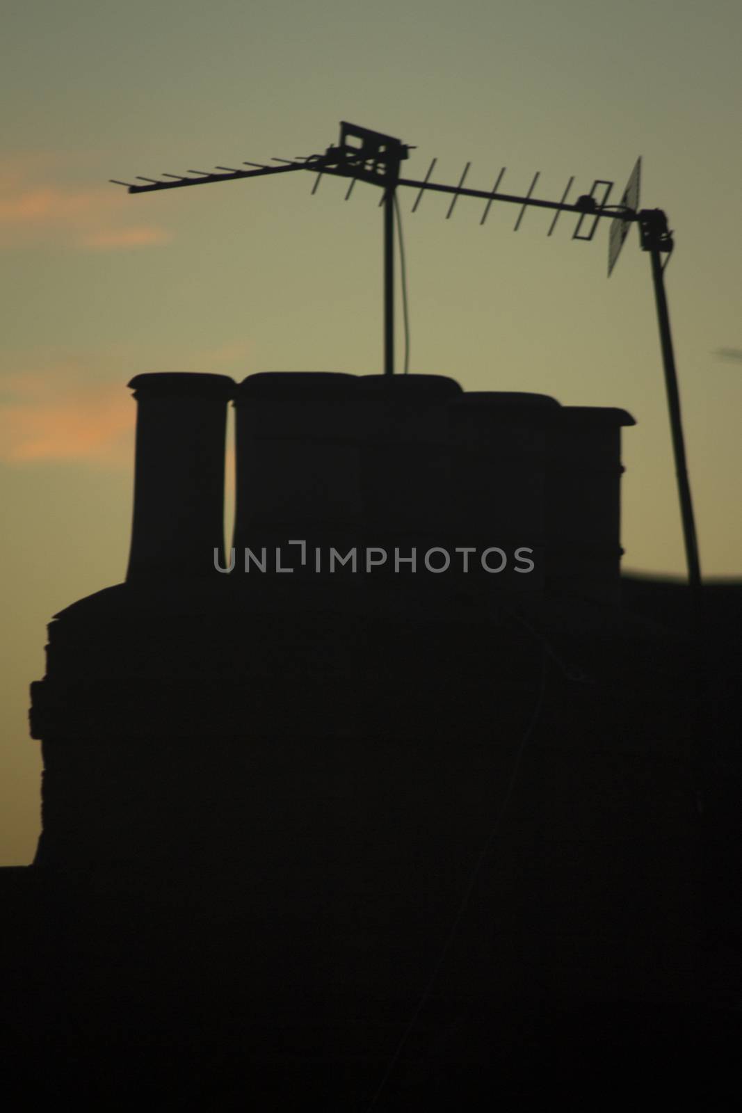 TV arial television antenna and chimney on roof of an urban high rise building and attractive blue purple dusk sunset sky in London England. 