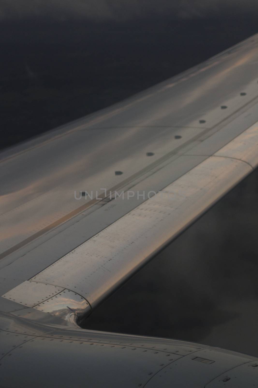 Airplane flying in grey sky in flight metal wing.
