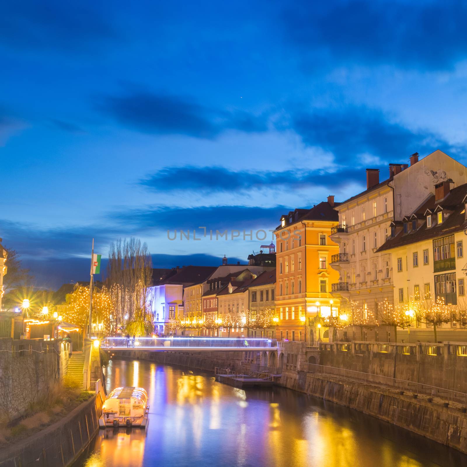 View of lively river Ljubljanica bank with new bridge in old city center decorated with Christmas lights. Ljubljana, Slovenia, Europe. Shot at dusk.