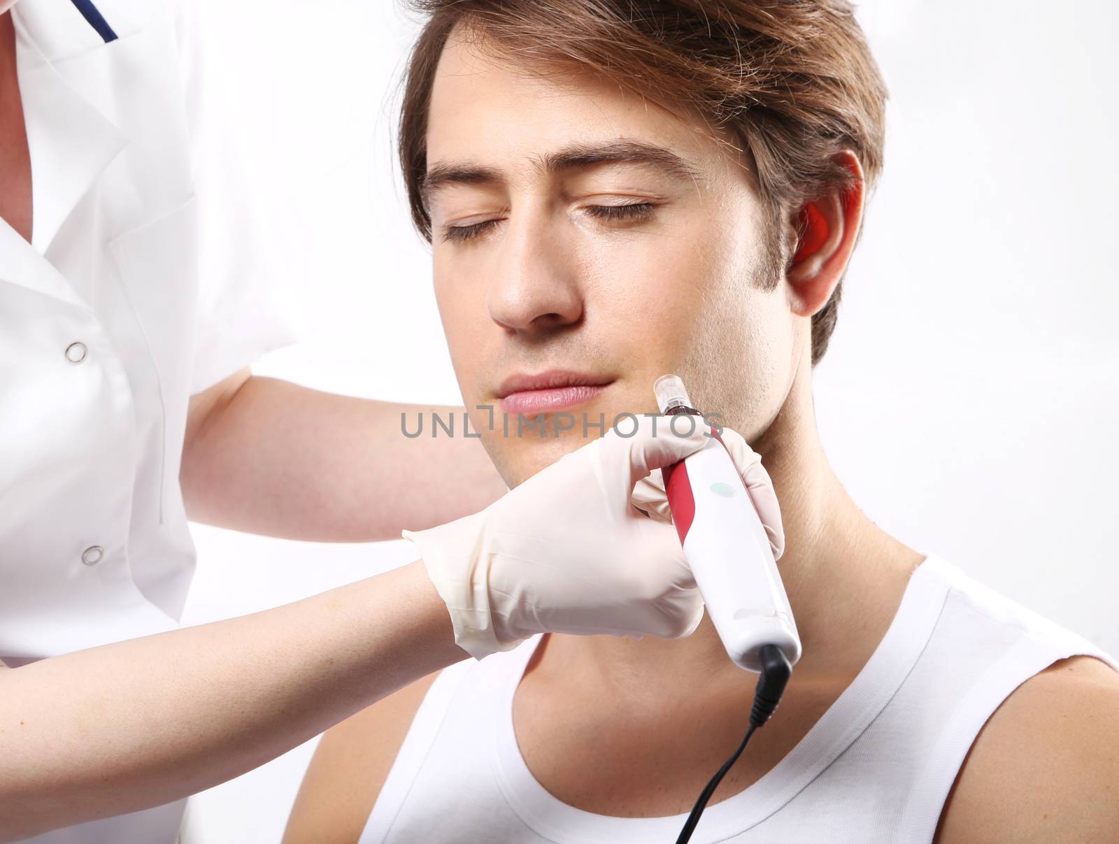 Handsome man during microdermabrasion treatment in beauty salon