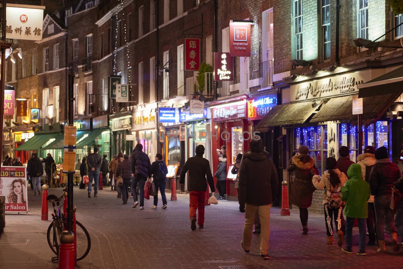 LONDON, UK - JANUARY 02: Pedestrians walking in traditional street lined with illuminated shop banners in Chinatown at night. January 02, 2015 in London.
