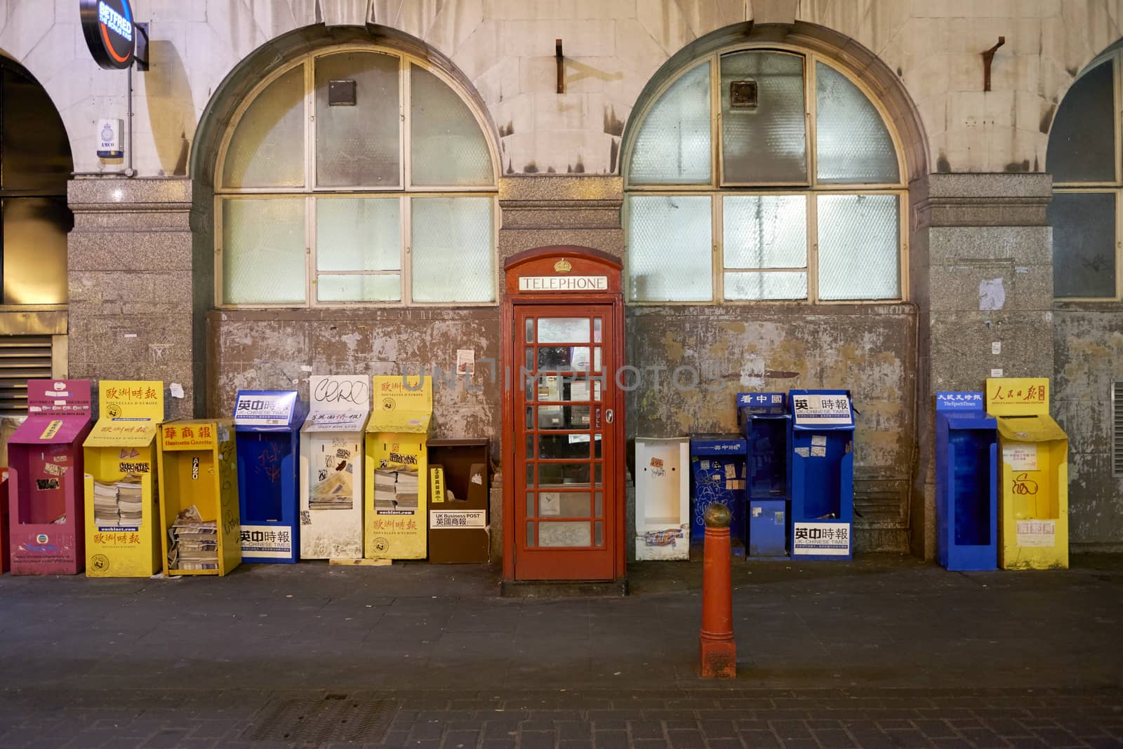 LONDON, UK - JANUARY 02: Traditional red telephone booth amongst Chinese language publications stands in the streets of Chinatown at night. January 02, 2015 in London.