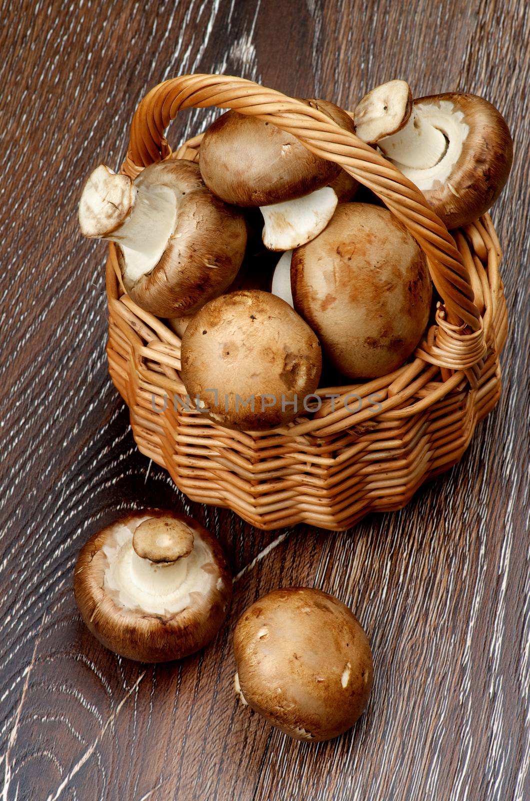 Gourmet Raw Portabello Mushrooms in Wicker Basket closeup on Dark Wooden background