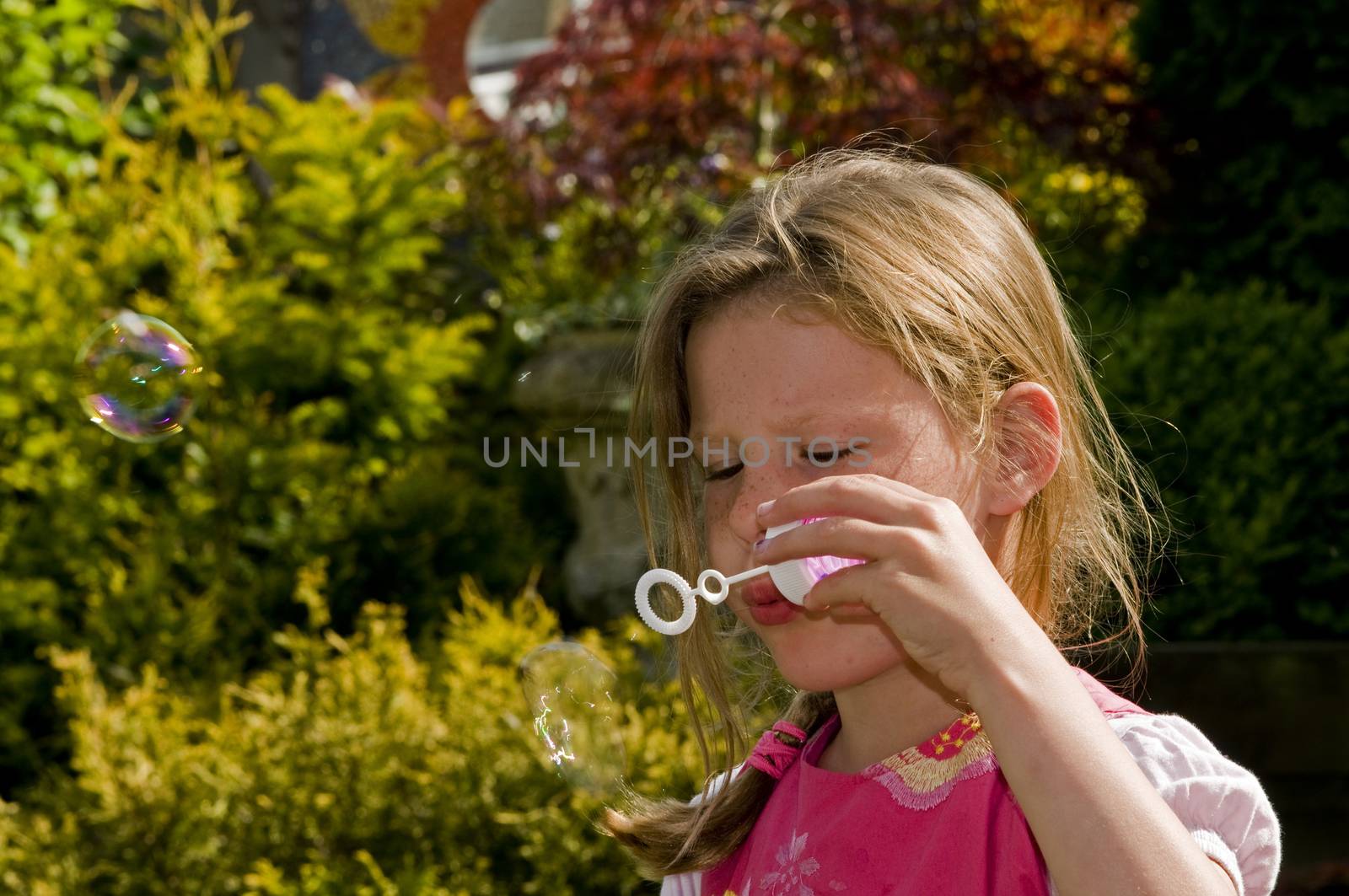 blond causcasian girl blowing bubbles by compuinfoto