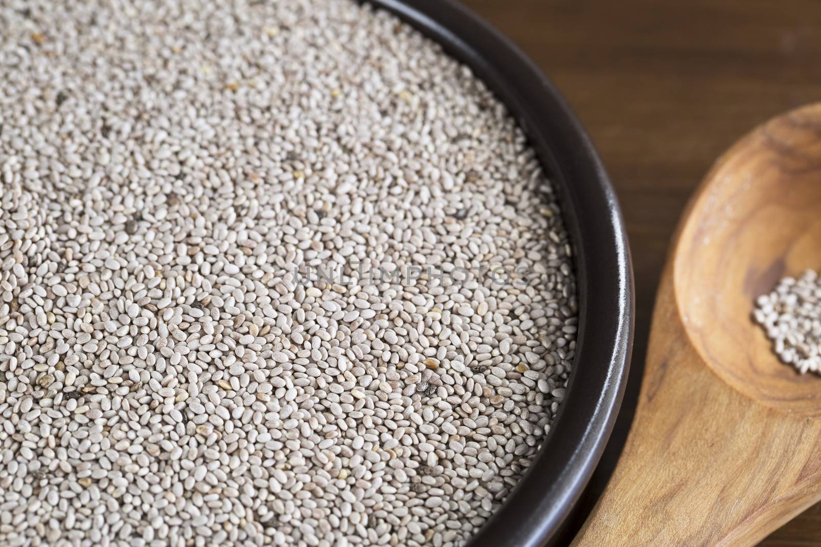 Healthy white chia seeds in bowl with wooden spoon.