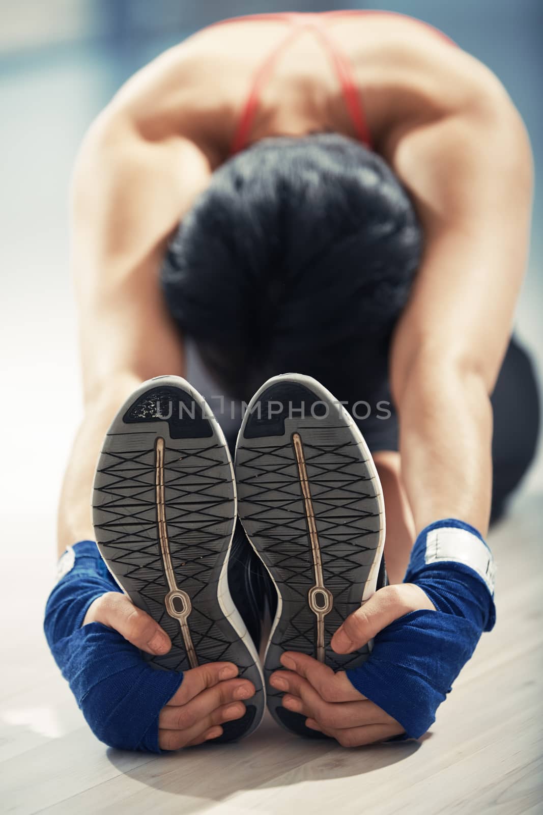 Stretching woman in exercising room by Novic