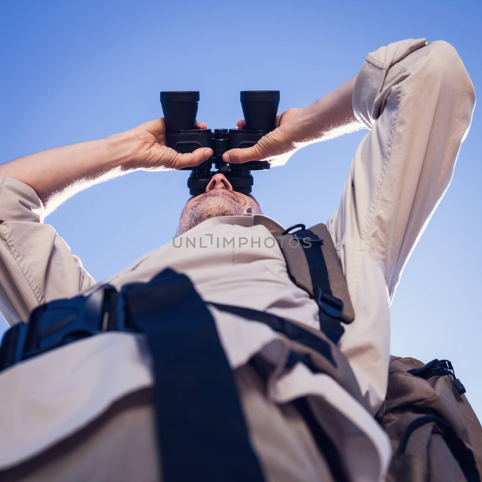 Hiker looking through binoculars on country trail by Wavebreakmedia