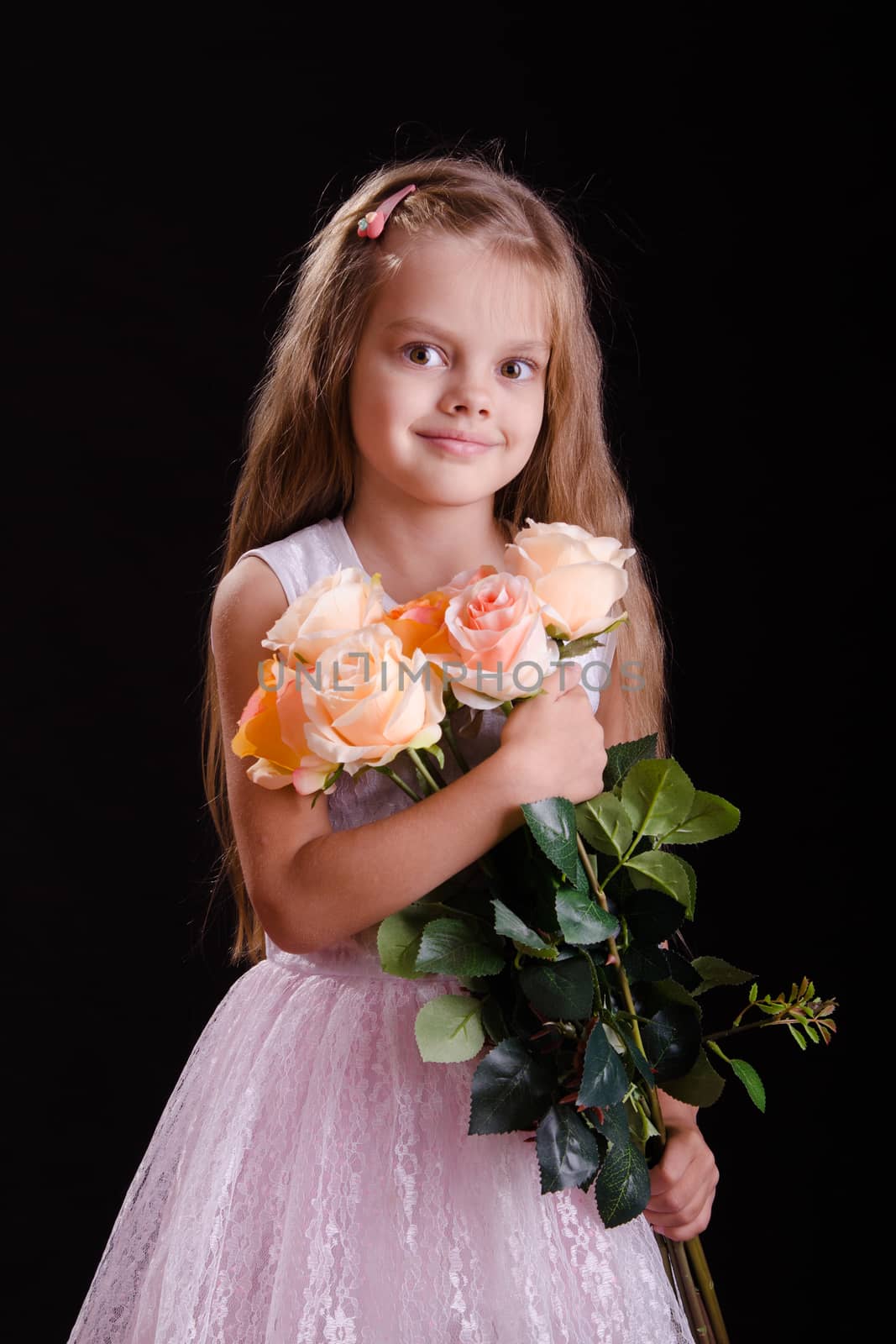 Portrait of a five year old girl with a bouquet of flowers on a black background