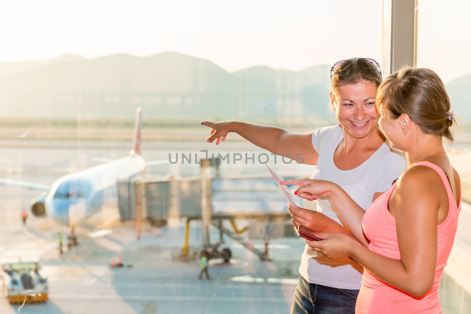 girl shows her friend a plane before take-off