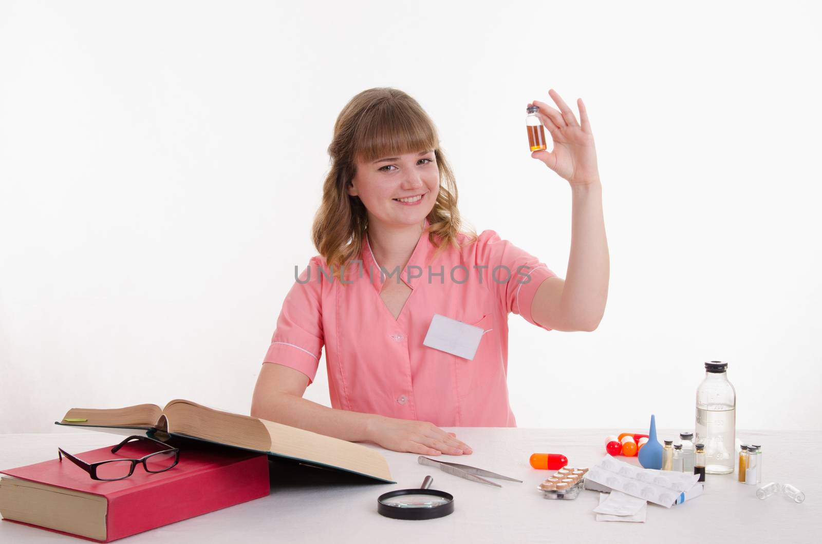 Pharmacist sitting at the table reading a thick handbook of medicines