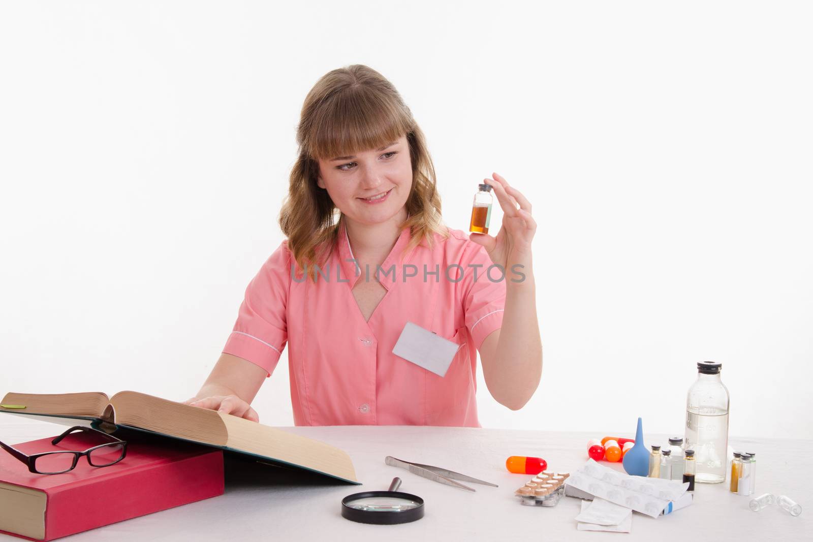 Pharmacist sitting at the table reading a thick handbook of medicines