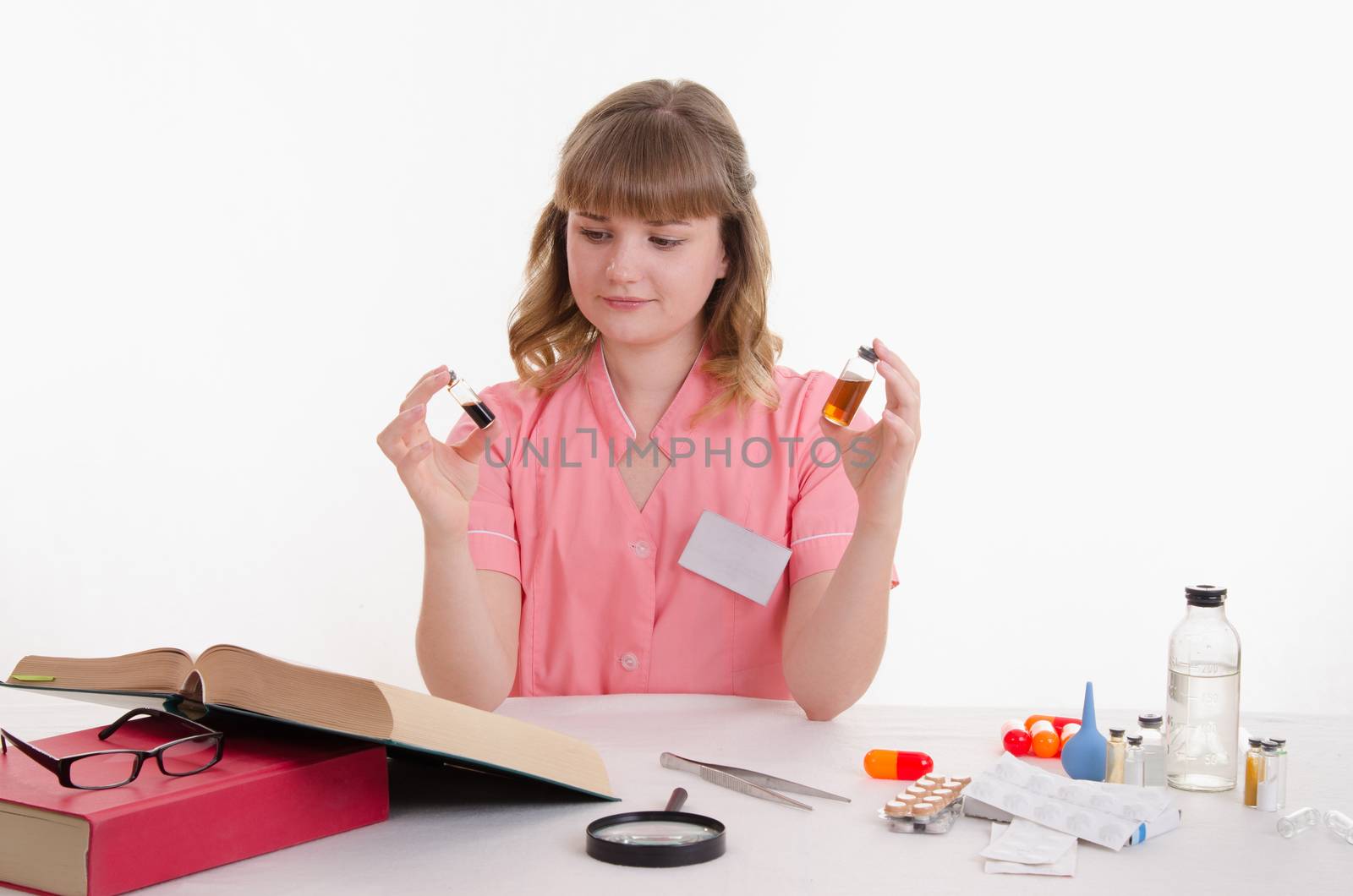 Pharmacist sitting at the table reading a thick handbook of medicines