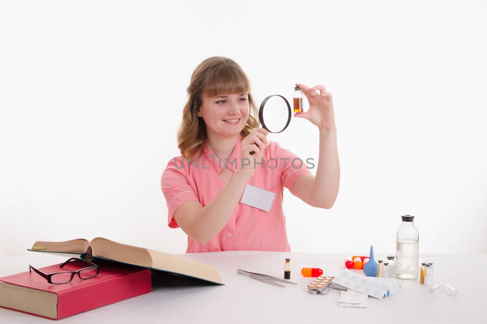 Pharmacist sitting at the table reading a thick handbook of medicines