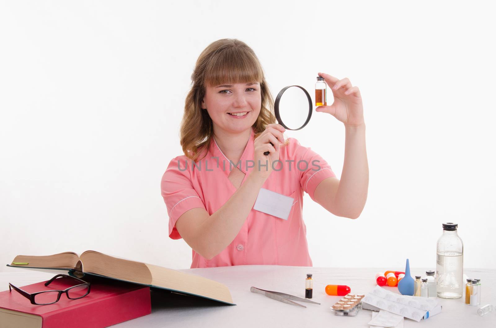Pharmacist sitting at the table reading a thick handbook of medicines