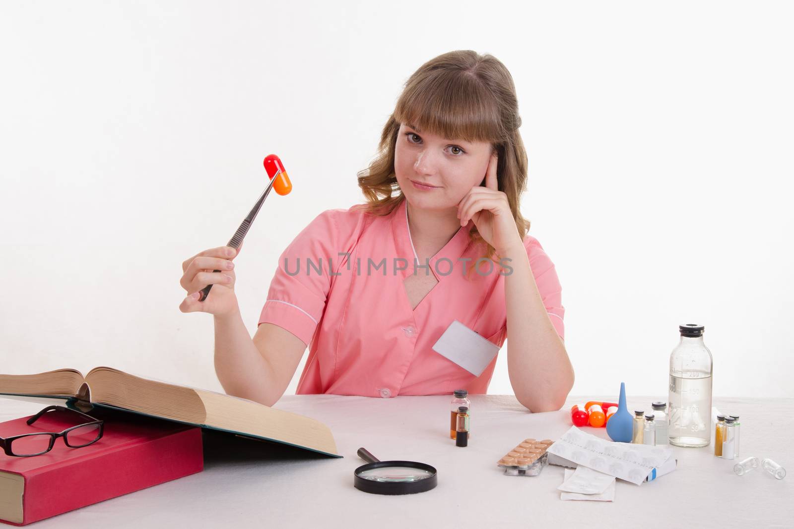 Pharmacist sitting at the table reading a thick handbook of medicines