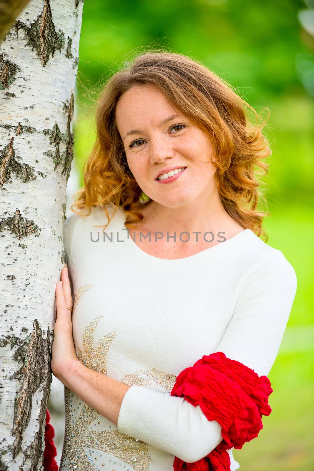 cute girl with a red scarf on nature near birch