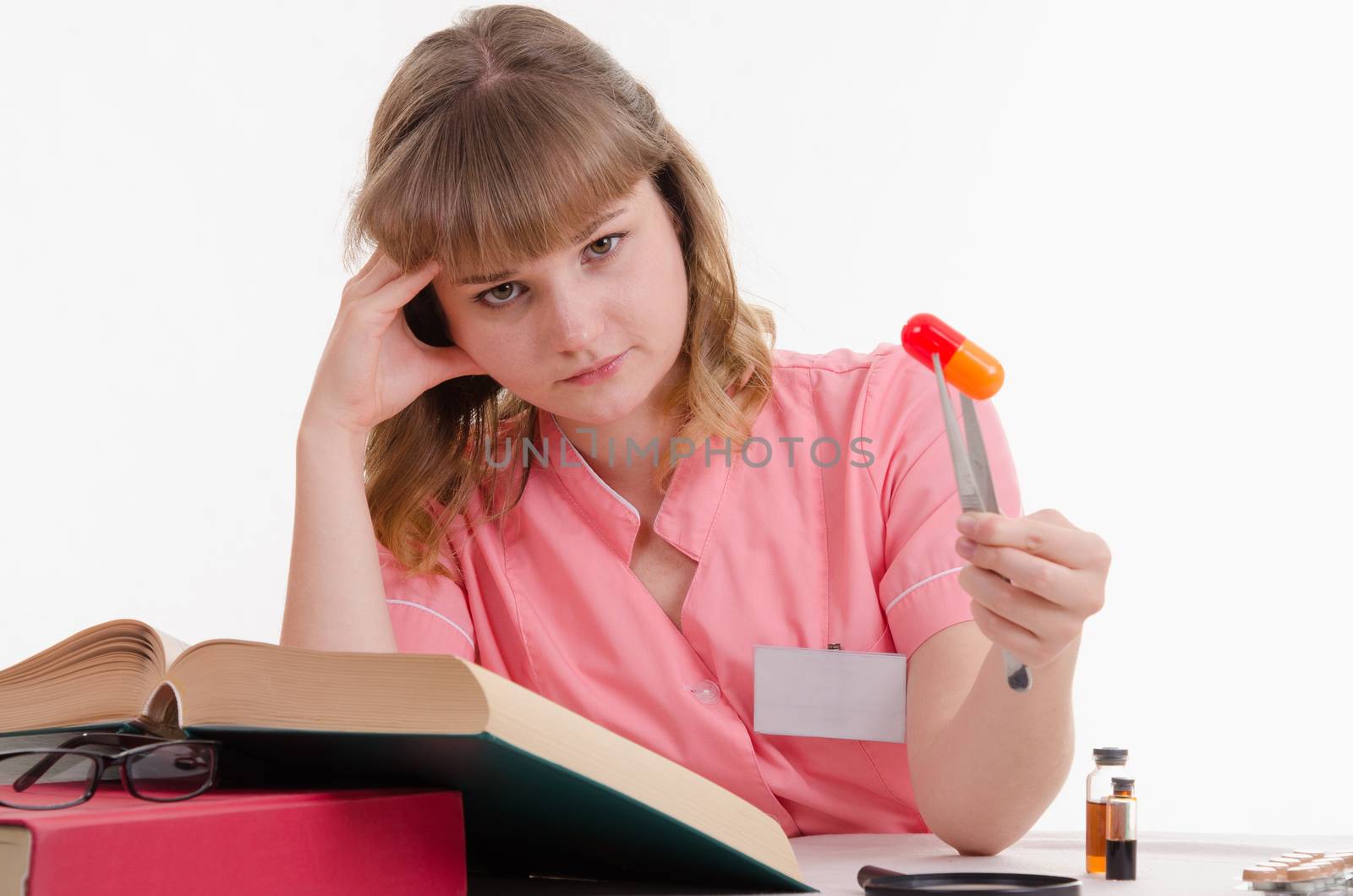 Pharmacist sitting at the table reading a thick handbook of medicines