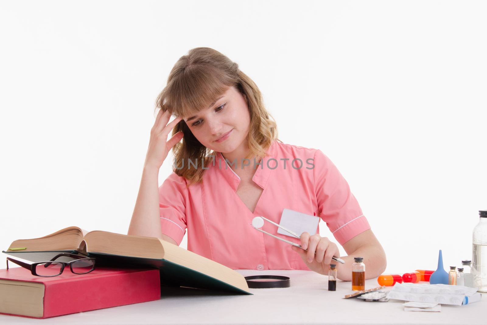 Pharmacist sitting at the table reading a thick handbook of medicines