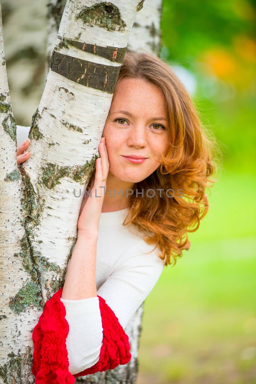 sweet young girl embraces a birch trunk