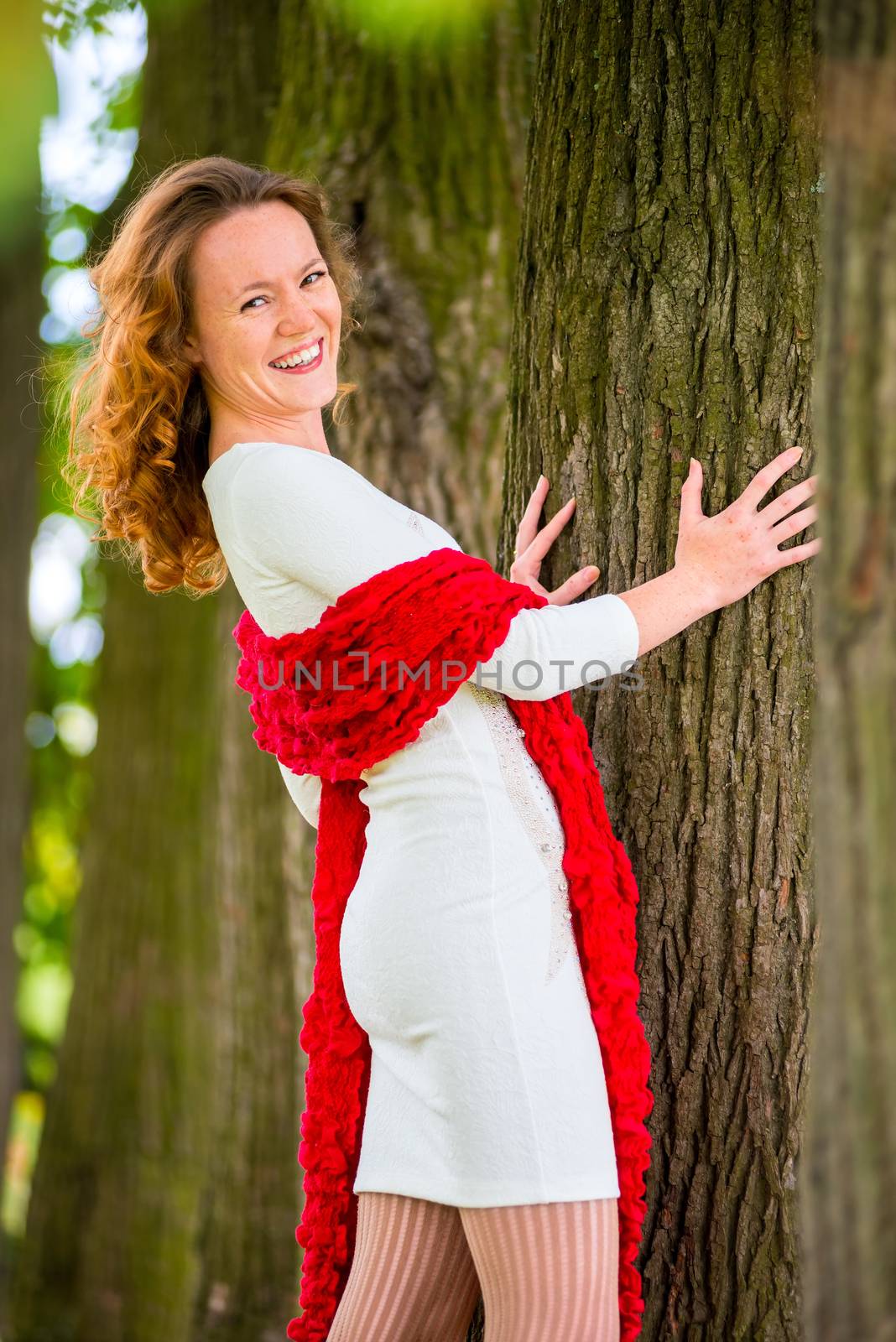 cheerful laughing girl posing in the summer park near tree