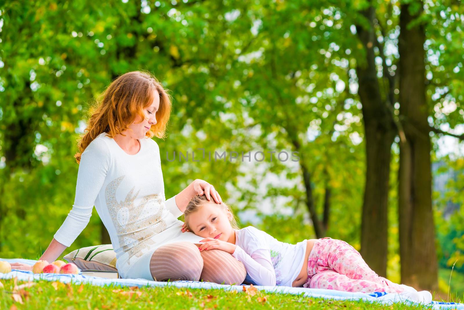 beautiful girl stroking her daughter on the lawn in the park