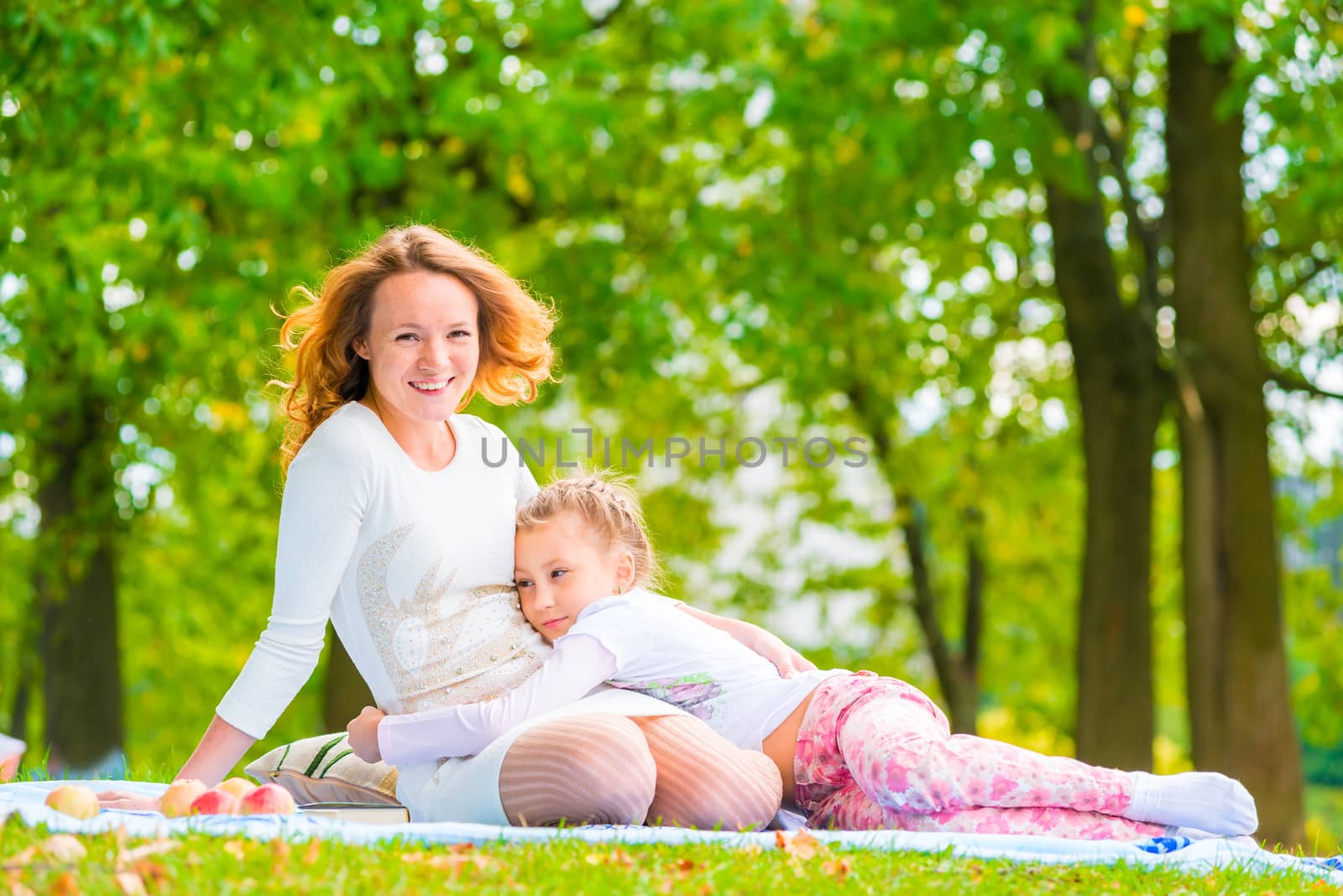 daughter embracing her mother lying on the lawn by kosmsos111