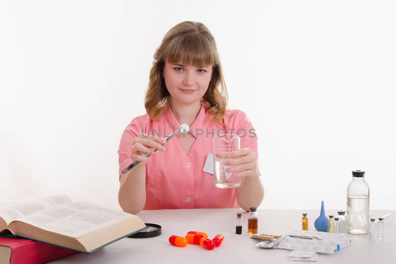 Pharmacist sitting at the table reading a thick handbook of medicines