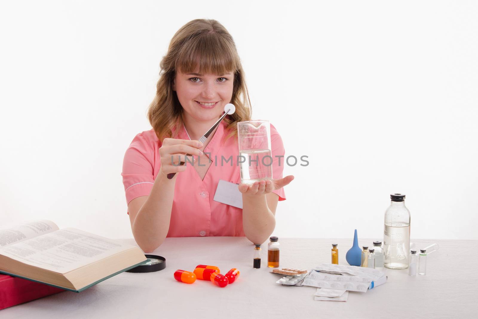 Pharmacist sitting at the table reading a thick handbook of medicines
