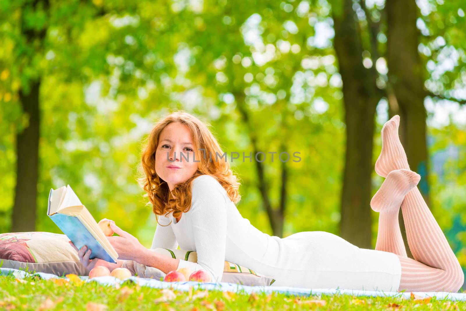 romantic girl with a good book and a delicious apple in the park