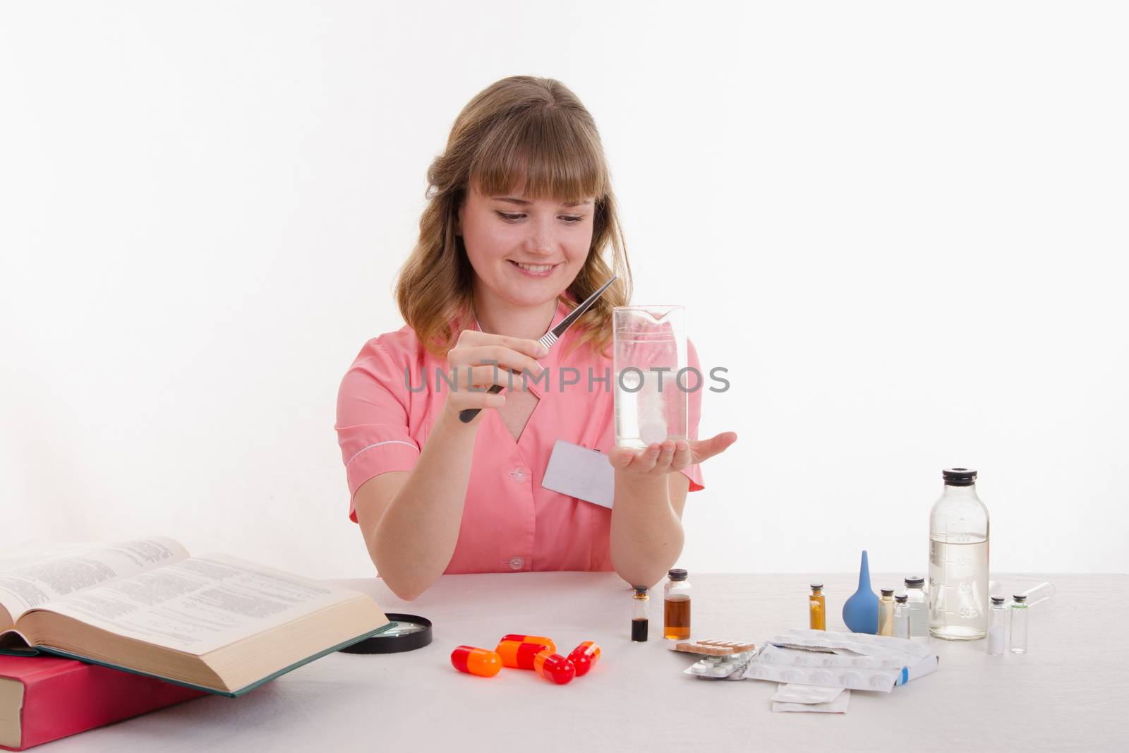 Pharmacist sitting at the table reading a thick handbook of medicines