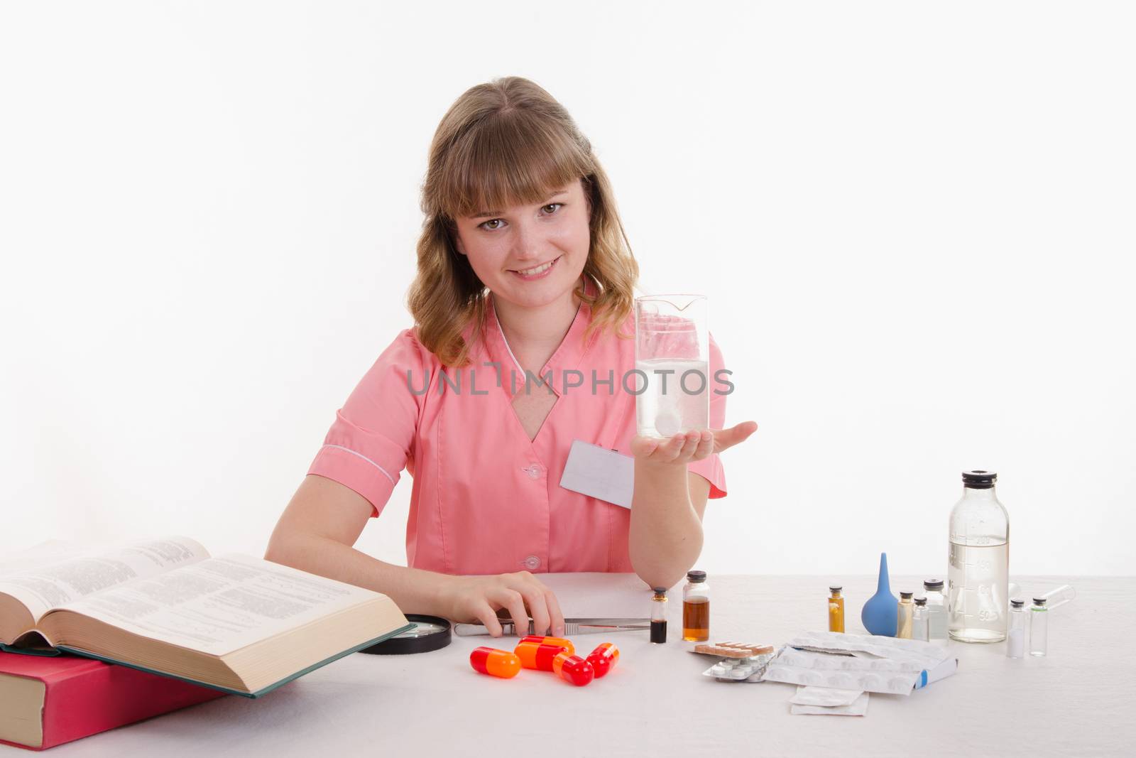 Pharmacist sitting at the table reading a thick handbook of medicines