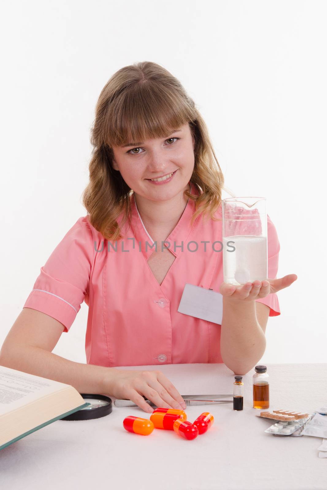 Pharmacist sitting at the table reading a thick handbook of medicines