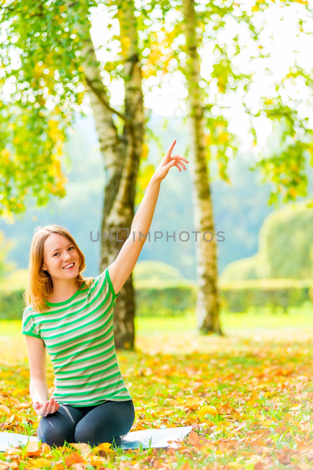 girl with a beautiful smile sitting in the park and shows the upstairs